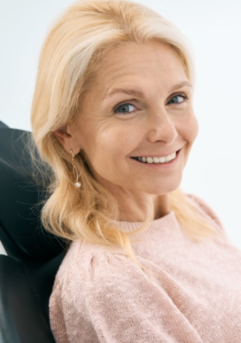 A mature woman smiling while sitting in the chair.